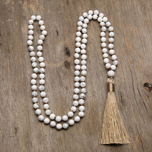 6mm knotted Howlite Mala with 108 beads and tassel on wooden surface.