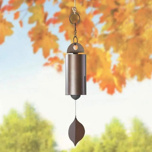 Metal wind chimes with retro design and leaf-shaped pendant against autumn backdrop.