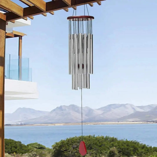 Serenity Blessings Wind Chimes with 27 aluminum tubes hang outdoors, creating peaceful sounds against a scenic background.